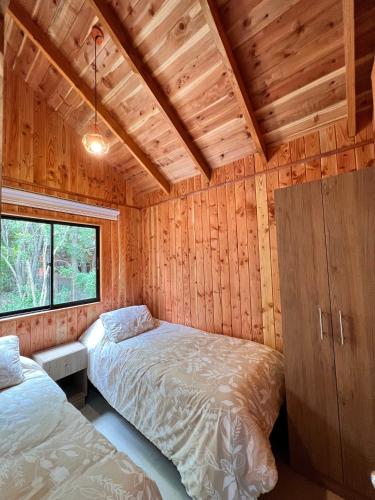 a bedroom with two beds in a wooden cabin at Cabañas Entre Árboles Pucón in Pucón