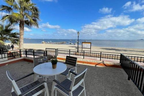 a table and chairs on a beach with the ocean at Charming Beachfront apartment in Murcia