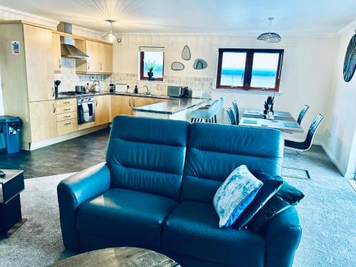 Central Cosy Riverview Apartment 2 bed, 2 bath, Free Parking / WiFi في إينفيرنيس: غرفة معيشة مع أريكة زرقاء ومطبخ