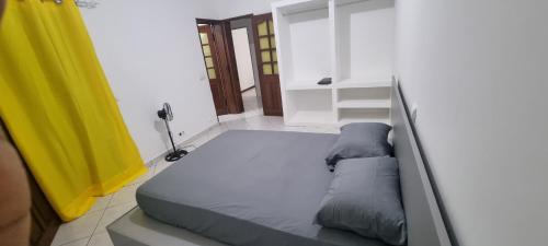 a bed in a room with a yellow curtain at Casa Cor de Rosa in Praia