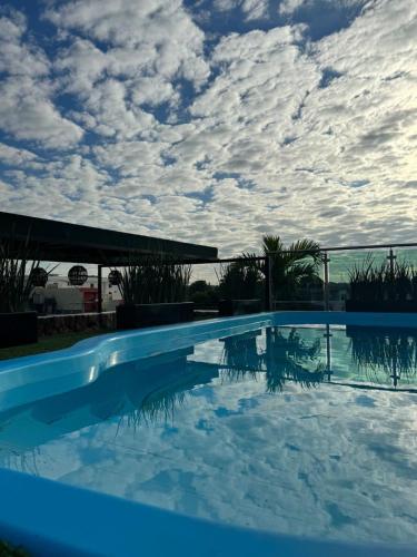 a blue swimming pool with a cloudy sky in the background at Royal Madero Inn Express in Tampico