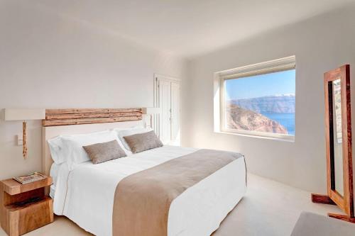 a white bedroom with a large bed and a window at Mystique, a Luxury Collection Hotel, Santorini in Oia