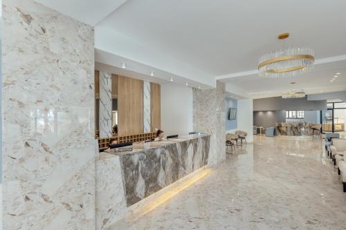 a large lobby with marble walls and a bar at Depadans Hotela TALIA in Igalo