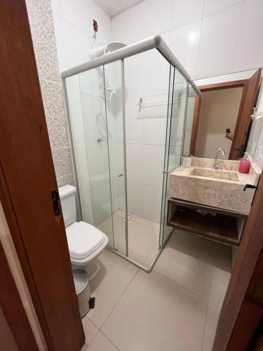 a bathroom with a shower and a toilet and a sink at Casinha na praia in Imbé