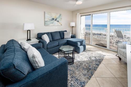 ein Wohnzimmer mit einem blauen Sofa und einem Balkon in der Unterkunft Gulf Dunes 312 by Brooks and Shorey Resorts condo in Fort Walton Beach