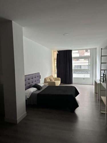 a bedroom with a bed and a chair and a window at Apartamentos RK 13 in Bilbao
