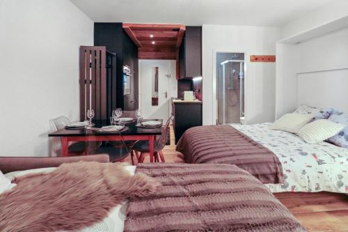 een slaapkamer met 2 bedden, een tafel en een bureau bij Studio rénové cosy et centré, Ski-In Ski-Out in Crans-Montana