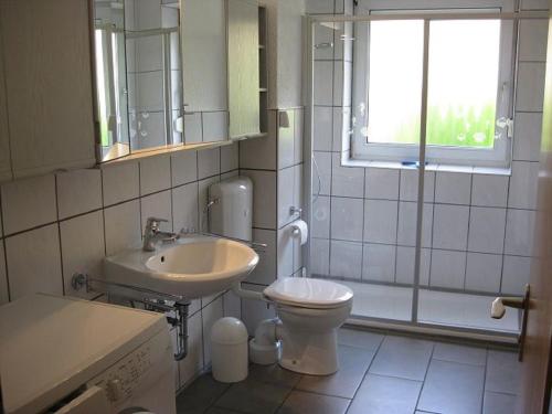 ein Bad mit einem Waschbecken, einem WC und einem Fenster in der Unterkunft Ernst-Gock Weg 07 in Duhnen