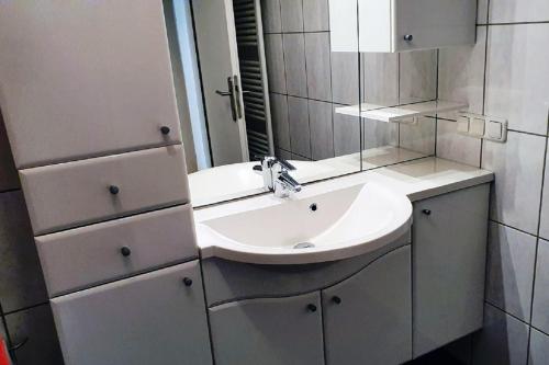 La salle de bains est pourvue d'un lavabo blanc et d'un miroir. dans l'établissement Panorama 36, à Duhnen