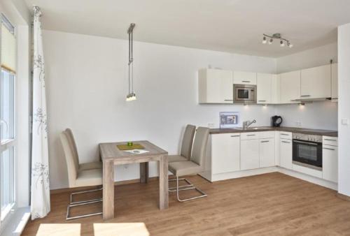 uma cozinha com armários brancos e uma mesa e cadeiras em Op de Geest 15 em Cuxhaven