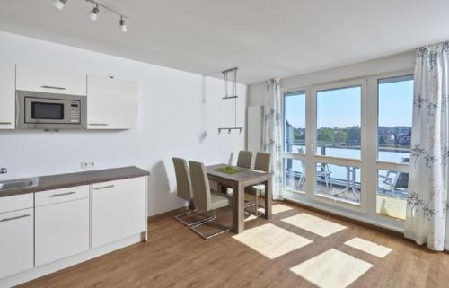 een witte keuken met een tafel en een balkon bij Op de Geest 16 in Cuxhaven
