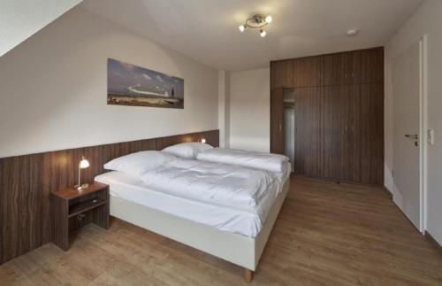 een slaapkamer met een wit bed en een houten muur bij Op de Geest 16 in Cuxhaven