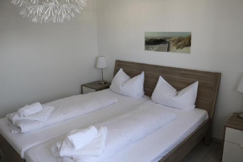 a white bed with white pillows on top of it at Nordsee 04 in Duhnen