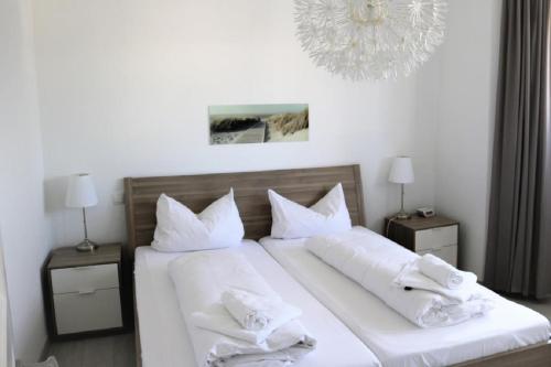 a bedroom with two beds with white pillows and a chandelier at Nordsee 03 in Duhnen