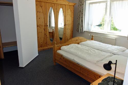 a bedroom with a wooden bed and two windows at Padua 4A in Duhnen