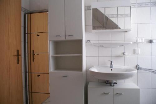 bagno bianco con lavandino e specchio di Oasis 09 a Cuxhaven