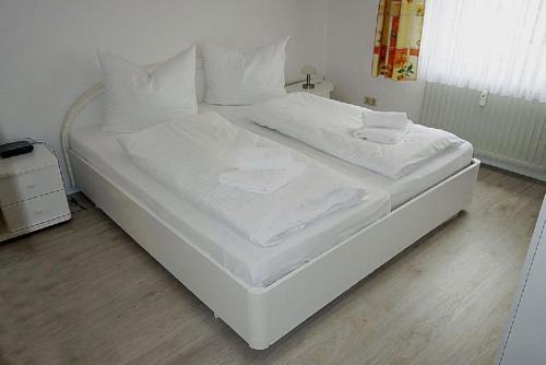 uma grande cama branca com lençóis e almofadas brancos em Gorch Fock 04 em Duhnen