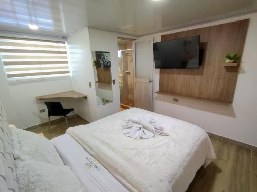 um quarto com uma cama e uma televisão na parede em Hotel Casa Baquero em Bogotá