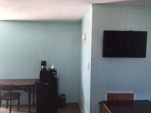 Habitación con pared azul y TV en la pared. en Northland Motel Bay City-Kawkawlin, en Kawkawlin