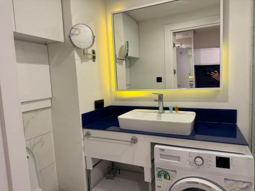 La salle de bains est pourvue d'un lavabo, d'un miroir et d'un lave-linge. dans l'établissement Sea View Panoramic Suite Orbi City, à Batoumi