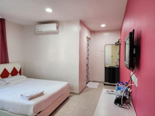 een slaapkamer met een wit bed en een roze muur bij Minshu RoomStay in Arau