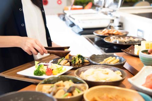 a person preparing food in a buffet line at Richmond Hotel Utsunomiya-ekimae Annex in Utsunomiya