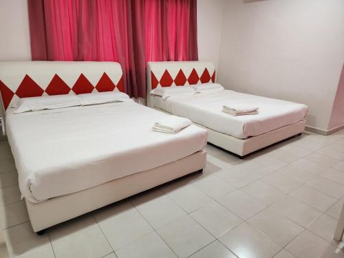 duas camas num quarto com cortinas cor-de-rosa em Minshu RoomStay em Arau