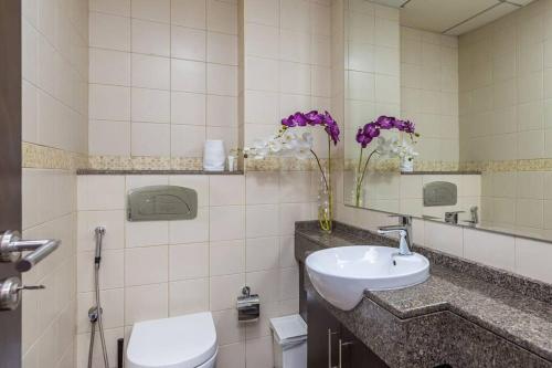 een badkamer met een wastafel, een toilet en bloemen bij Your Cosy Marina Retreat in Dubai