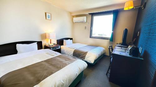 a hotel room with two beds and a flat screen tv at Hotel Honjo in Honjo
