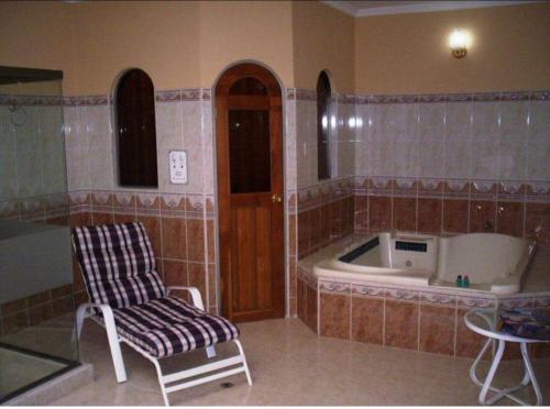 a bath room with a tub and a chair and a chair at Aparta Hotel Plenitud in Palmira