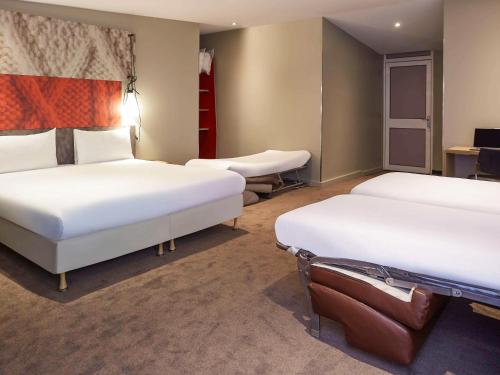 a hotel room with two beds and a desk at ibis Paris Canal Saint Martin in Paris