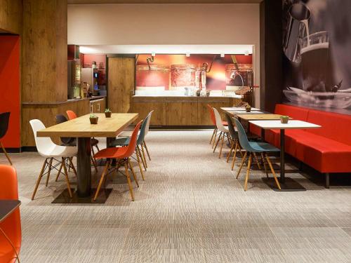 un ristorante con tavoli e sedie in legno e una cucina di ibis Paris Canal Saint Martin a Parigi