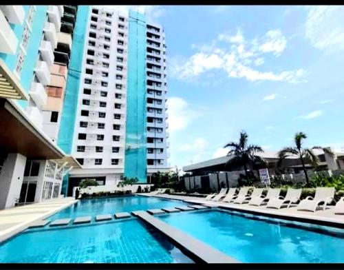 a swimming pool with chairs and a tall building at Tehillah Residences in Bacolod