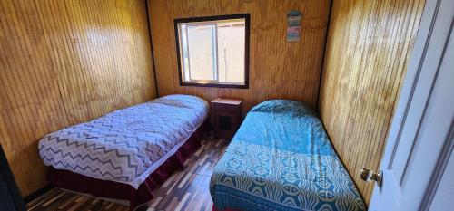 a small room with two beds and a window at Cabaña buck in Dalcahue
