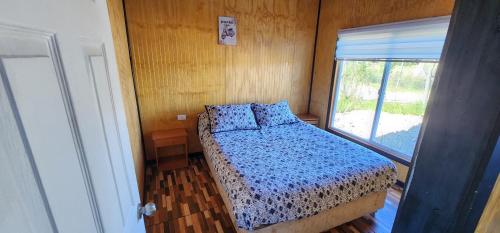 a small bedroom with a bed and a window at Cabaña buck in Dalcahue