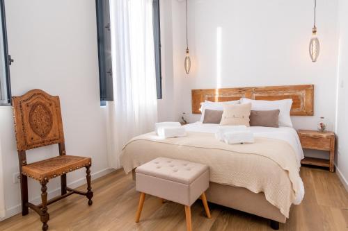 a bedroom with a large bed and a chair at Apartamentos do Mercado in Covilhã