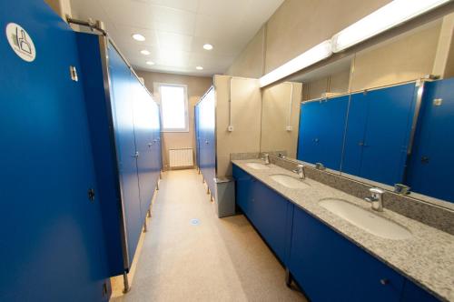 a bathroom with three sinks and blue stalls at L'Espluga de Francolí Xanascat in Espluga de Francolí