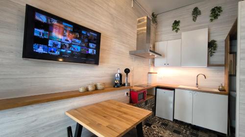 a kitchen with a table and a tv on the wall at L'Excursion - Charmant T2 Rénové proche de la mer in Cassis