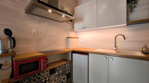 a kitchen with white cabinets and a red microwave at L'Excursion - Charmant T2 Rénové proche de la mer in Cassis
