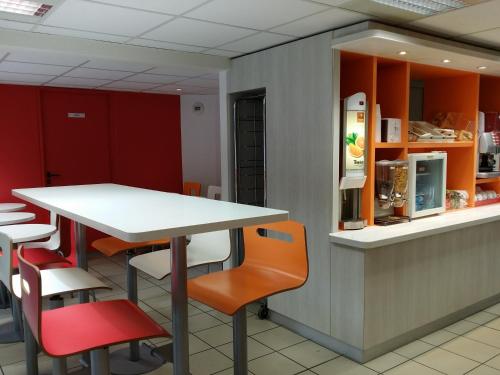a restaurant with a white table and orange chairs at Première Classe Valence Sud in Valence
