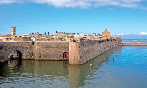 un vecchio muro di pietra con una città sullo sfondo di Art studio mazighen a El Jadida