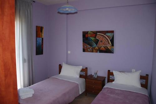 two beds in a room with purple walls at Nikos Apartments in Ioannina