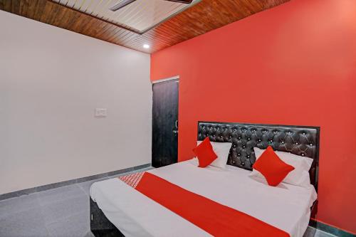 a bedroom with a red wall and a bed at The Cawnpore Inn in Kānpur