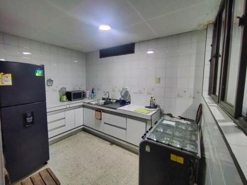 uma cozinha com paredes brancas e um frigorífico preto em Hostal, casa Jaramillo em Roldanillo