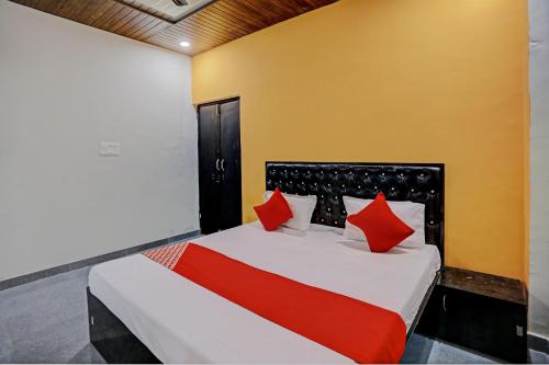 a bedroom with a large bed with red pillows at The Cawnpore Inn in Kānpur
