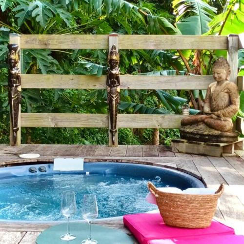 a statue of a buddha sitting next to a pool at Cabane intime Nid’Amour, Jacuzzi privé in La Plaine