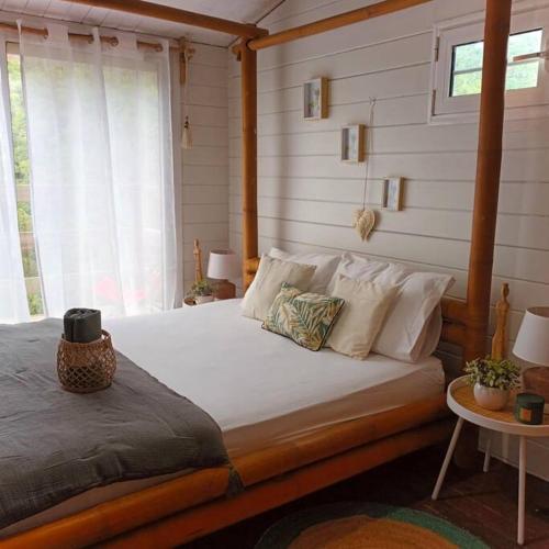 a bedroom with a bed with white sheets and a window at Cabane intime Nid’Amour, Jacuzzi privé in La Plaine