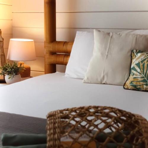 a bed with white sheets and pillows and a lamp at Cabane intime Nid’Amour, Jacuzzi privé in La Plaine