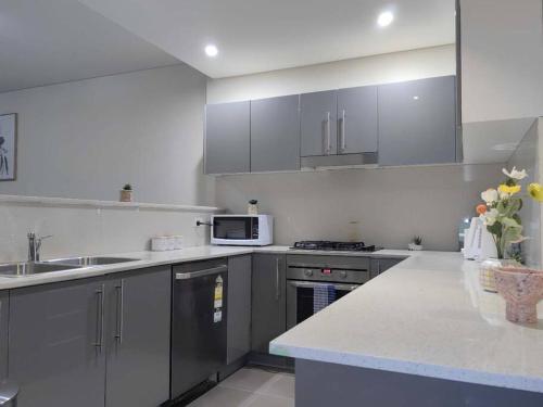 a kitchen with gray cabinets and a white counter top at Entire 3 bed apartment in Ryde in Sydney