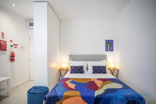 een slaapkamer met een bed met een kleurrijke deken en kussens bij Porto Formosa Central Lofts in Porto